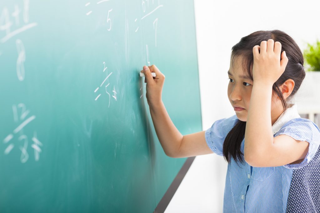 school girl doing math problems on the chalkboard
