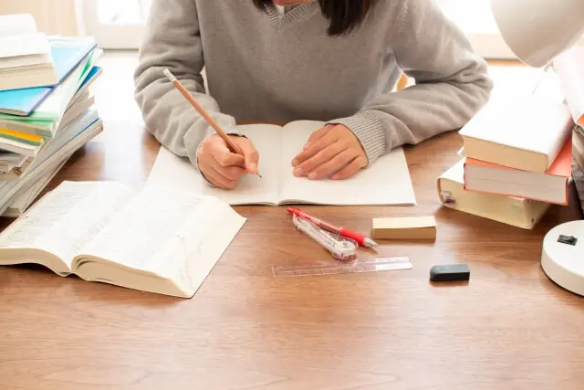 参考書や教科書を広げて勉強している女子生徒