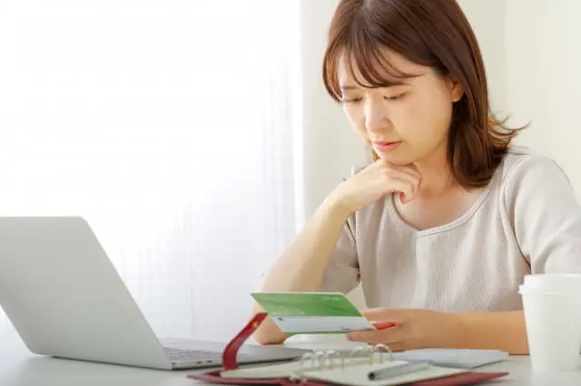 通帳を見て悩む女性